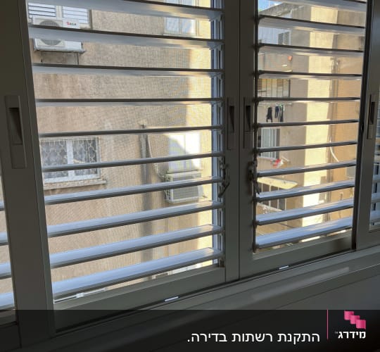 תריסי אלומיניום בחלון פנימי עם נוף חיצוני